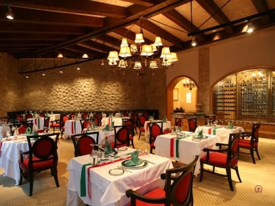 Elegancka sala restauracyjna w klasycznym stylu z kamiennymi ścianami i ciepłym oświetleniem.