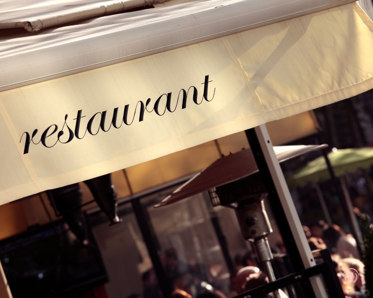 Markiza restauracji z napisem "restaurant" w ciepłym świetle popołudnia, zapraszająca do eleganckiego miejsca spotkań.
