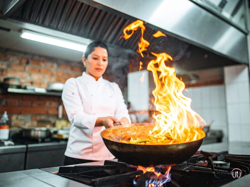 Szefowa kuchni Lena Wysocka w białej marynarce ozdabia fine diningowe danie świeżym szczypiorkiem.