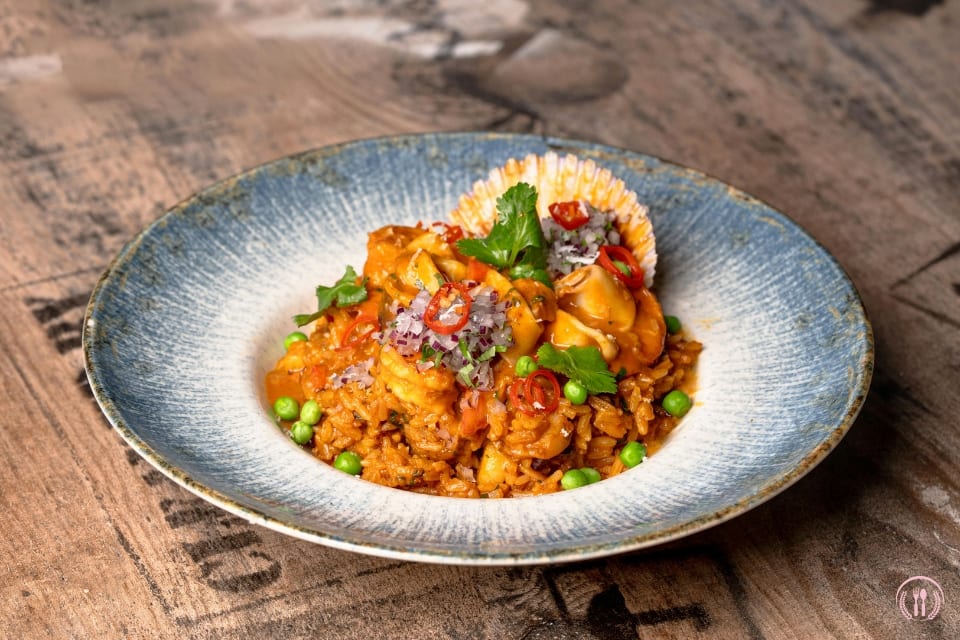 Risotto z karmelizowaną gruszką i szałwią, podane z parmezanem i listkami świeżych ziół.